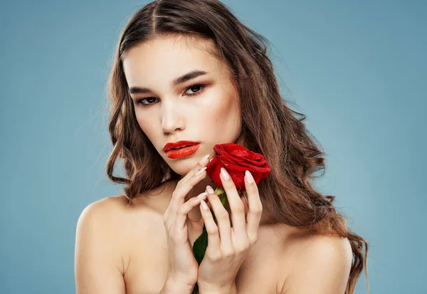 Vrouw model met rode roos nabij gezicht op blauwe achtergrond — Stockfoto