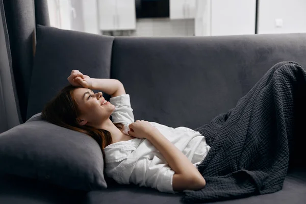 Emocjonalne kobieta leży na kanapie i miękkie poduszki wnętrze przycięte widok — Zdjęcie stockowe