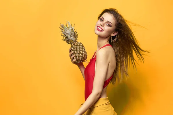 Vacker kvinna med ananas i händerna kosmetika exotiska frukter gul bakgrund kul — Stockfoto