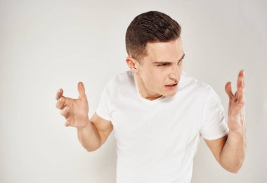 Beyaz tişörtlü, duygusal, asabi, hafif arka planlı bir adam.