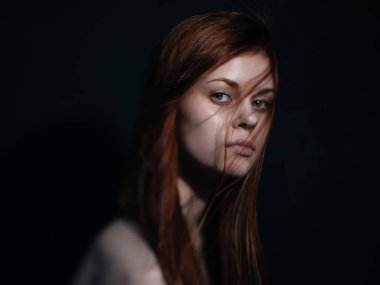 Karanlık arka plan görünümlü bir modelle ilgilenen bir kadın.