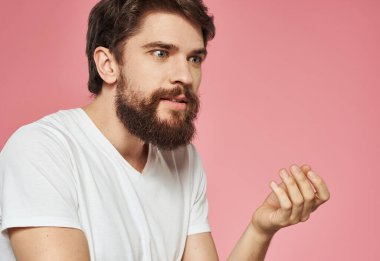 Kafası karışmış, elleri yana bakan, pembe arka planı olan bir adam.