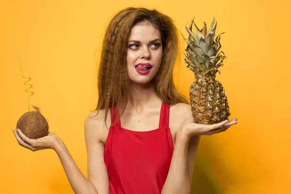 Frau mit Kokoscocktail Ananas in den Händen und kritischen Früchten Rotes T-Shirt gelber Hintergrund — Stockfoto