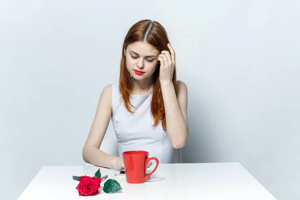 Frau sitzt am Tisch Tasse mit Getränk rote Rose — Stockfoto