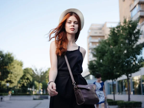 Mujer bonita en una camiseta negra y sombrero están caminando en la calle cerca del edificio —  Fotos de Stock