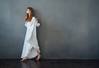 Çekici kadın, beyaz elbise, lüks performans stüdyosu gri arka plan.