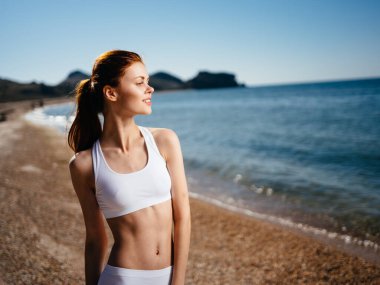 Beyaz mayo giymiş bir kadın plaj adası manzarası güneşinde yürüyor.