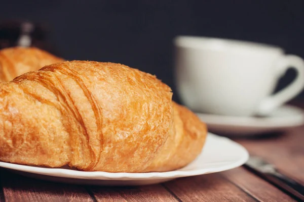 Croissants pratos brancos na mesa utensílios de cozinha uma xícara de café sobremesa refeição — Fotografia de Stock