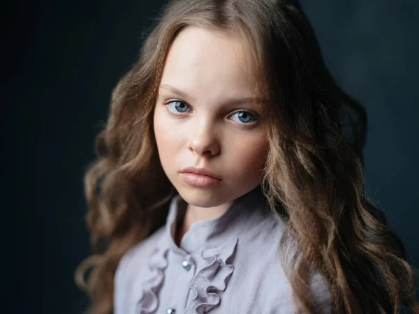 Retrato de una hermosa chica con el pelo rizado y un vestido gris sobre un fondo oscuro — Foto de Stock