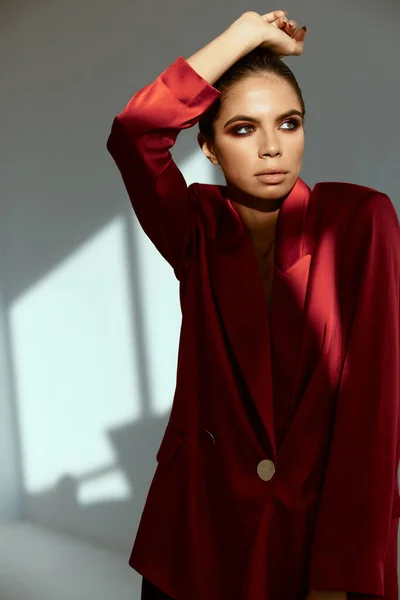 Morena bonita segurando sua mão acima de sua cabeça casaco vermelho moda estúdio decoração — Fotografia de Stock