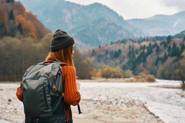 Mulher com uma mochila perto do rio na natureza nas montanhas — Fotografia de Stock