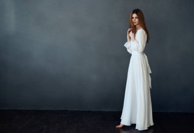 Beyaz elbiseli güzel kadın çekici görünüyor. Lüks cazibeli gri arka plan modeli.