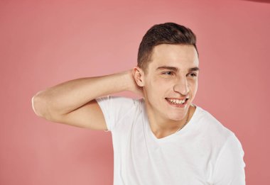 Beyaz tişörtlü yakışıklı adam pembe arka planda.