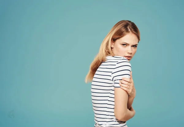 Offended woman in a T-shirt turned her back to the side on a blue background — Stock Photo, Image