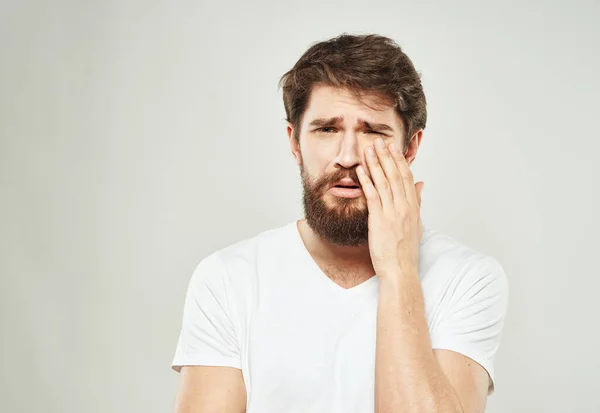 Ein Mann im weißen T-Shirt vor hellem Hintergrund gestikuliert mit den Händen. — Stockfoto