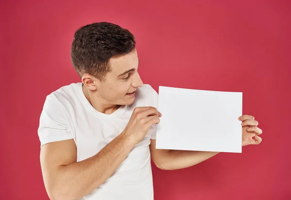 Man met een flyer in zijn hand op een rode achtergrond reclame mockup Copy Space — Stockfoto