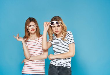 Kırgınlıklarını dile getiren iki kadın, hoşnutsuzluklarını gidermek için mavi arka planda tartışıyor.