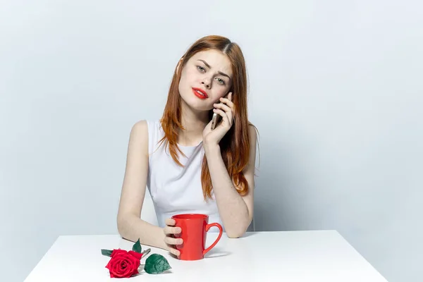 女人在电话里聊天，坐在茶杯边喝着红玫瑰 — 图库照片