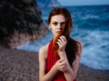 Güzel kadın, kırmızı elbise, lüks manzara, kayalık taş.