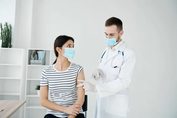 Il medico di sesso maschile in camice bianco effettua un'iniezione nella mano di una donna vaccinata — Foto Stock