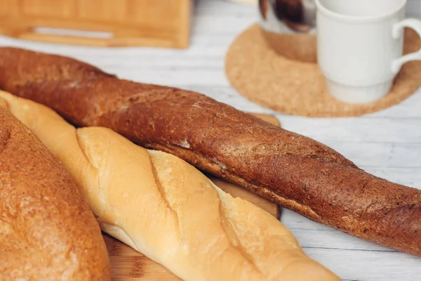 Świeże bochenki chleba na koszyku na śniadaniu stołowym — Zdjęcie stockowe