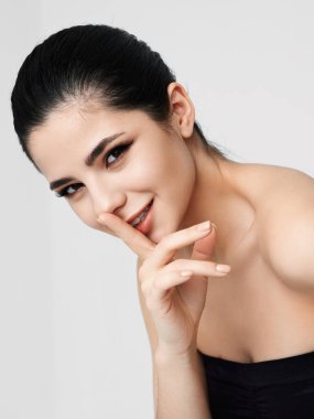 Güzel esmer, parmağını yüzüne yakın tutuyor. Çekici görünümlü stüdyo.