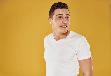 Tişörtlü bir adamın portresi. Sarı arka planda, yakın plan kırpılmış bir manzara.