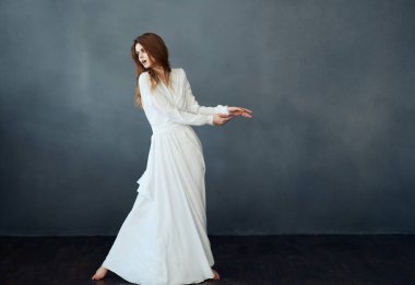 Gri arkaplan üzerinde beyaz elbiseli romantik kızıl saçlı kadın.