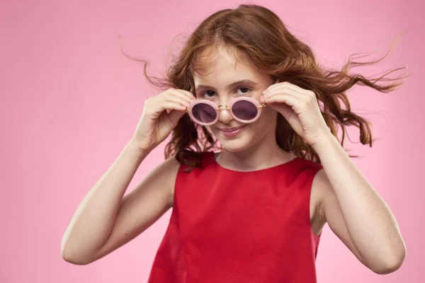 Κορίτσι με σγουρά μαλλιά γυαλιά ηλίου παιδική χαρά ροζ φόντο — Φωτογραφία Αρχείου