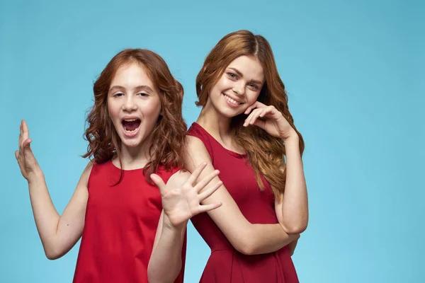 Mamá e hija en vestidos rojos entretenimiento estilo de vida divertido estudio fondo azul —  Fotos de Stock