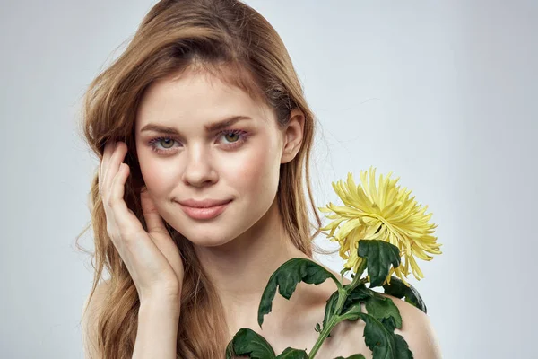 Portret pięknej kobiety z żółtym kwiatem na jasnym tle czarujący uśmiech model rude włosy — Zdjęcie stockowe