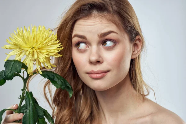 Portrait d'une belle femme avec une fleur jaune sur un fond clair charmant sourire modèle cheveux rouges — Photo