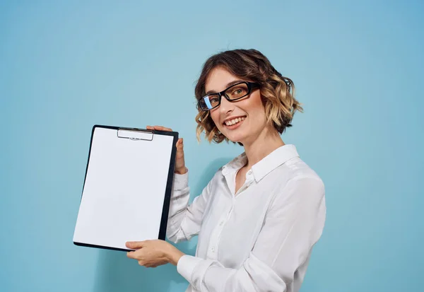 Mulher em um fundo azul com uma pasta de documentos nas mãos de uma folha branca de papel mockup — Fotografia de Stock