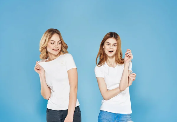 Két nő fehér pólóban barátságos érzelmek életmód kommunikáció kék háttér — Stock Fotó