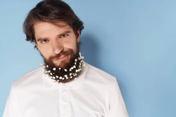 Homem emocional em uma camiseta branca flores em uma barba close-up fundo azul — Fotografia de Stock