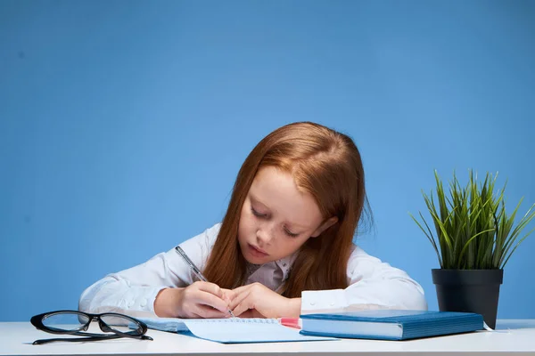 Menina sentada à mesa e fazendo aulas de educação escolar — Fotografia de Stock