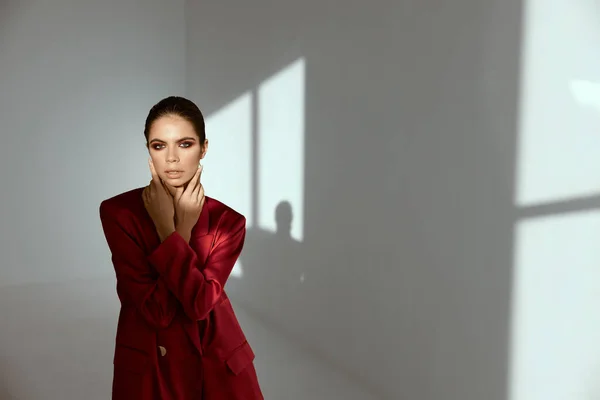 Uma mulher com uma jaqueta vermelha com maquiagem à noite em seu rosto Em um quarto escuro — Fotografia de Stock