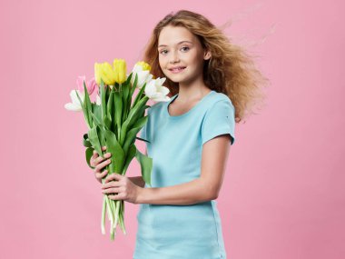 little girl with a bouquet of flowers spring pink background blue t-shirt