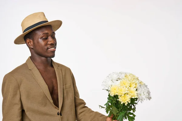 Chico de aspecto africano con un ramo de flores y un sombrero —  Fotos de Stock