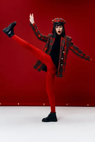 Emotional woman with her leg raised bright clothes red background — Photo