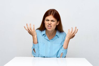 emotional woman in a shirt sits at the table gesture with the hands of the secretary