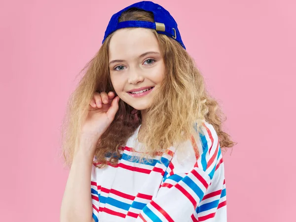 Girl in fashion clothes curly hair blue cap pink background — Photo