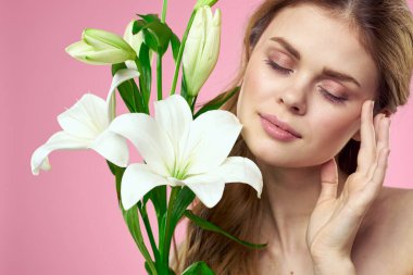 Pembe arka planda beyaz çiçekli güzel bir kadının portresi.