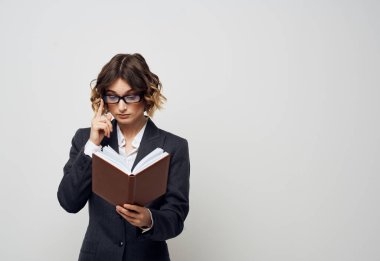 İş kadını elinde bir kitapla arka planı aydınlık görünüyor. Bulmaca gibi görünüyor.