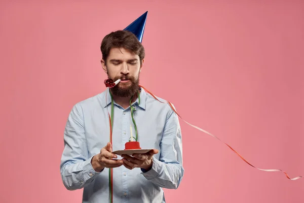 Hombre barbudo con lengua de pastel sobre un fondo rosa vista recortada y una gorra azul en la cabeza — Foto de Stock