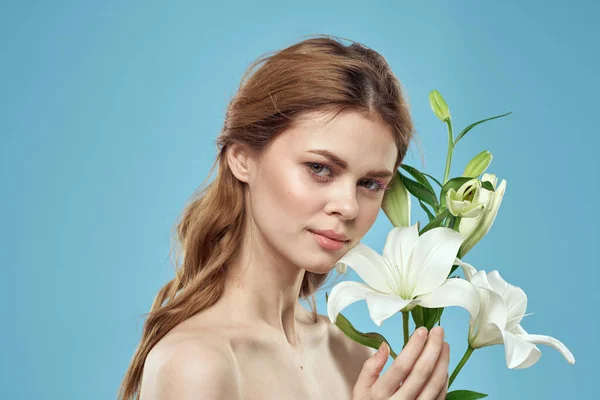 Žena s kyticí bílých květin na modrém pozadí nahá ramena krásná tvář — Stock fotografie