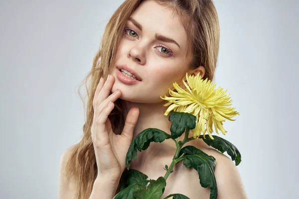 Retrato de una hermosa mujer con una flor amarilla sobre un fondo claro encantadora sonrisa modelo pelo rojo — Foto de Stock