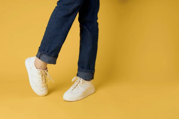 Modische Schuhe weiße Turnschuhe Beine gelb Hintergrund abgeschnitten Ansicht — Stockfoto