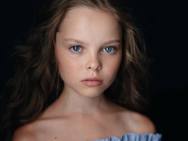 Koyu arkaplanda, açık arkaplan portresi giymiş bir kız.