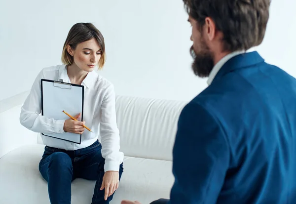 Hombre de negocios en un traje clásico y una mujer en el sofá con documentos en sus manos — Foto de Stock